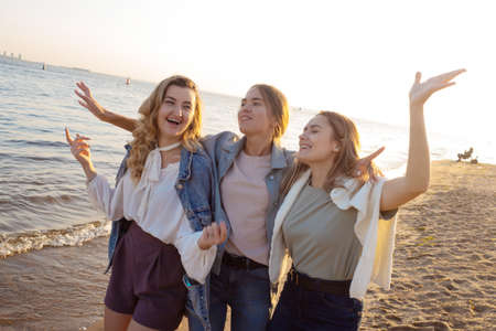 Three friends having fun on the beach, meeting friends. Young womenの写真素材