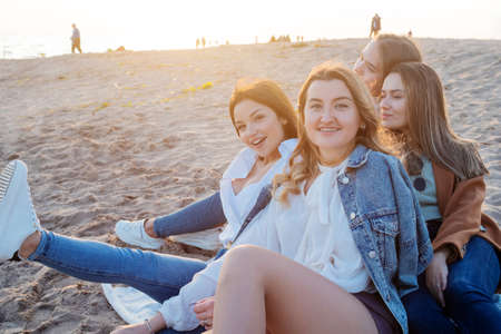 Group of young women on a picnic on the beach, enjoying the sunset. Meeting friends,の写真素材