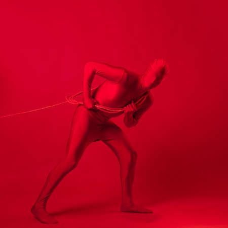 an anxious red man in a red leotard, dragging a heavy burden,の写真素材