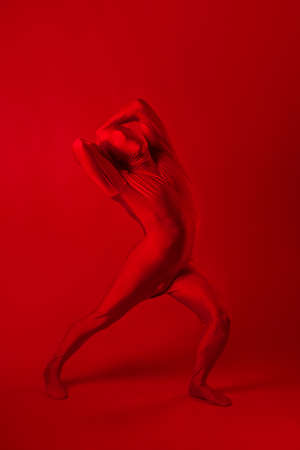 A screaming man in a red full suit, on a red background.の写真素材