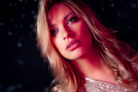 Mysterious portrait of a beautiful young blonde with drops on the glassの写真素材