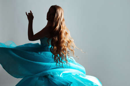 mysterious young woman with long wavy hair and a lush blue dress.の写真素材