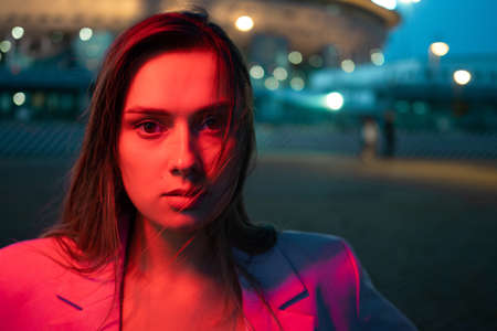 A young stylish brunette in the lights of the night city, neon lighting,
