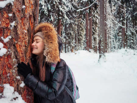 A happy smiling woman in warm clothes with a hood on her head hugsの写真素材