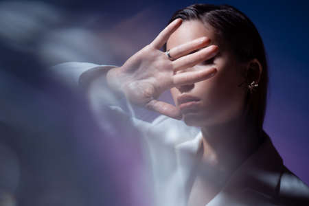 young woman covers her face with her hands, hides and says stop.