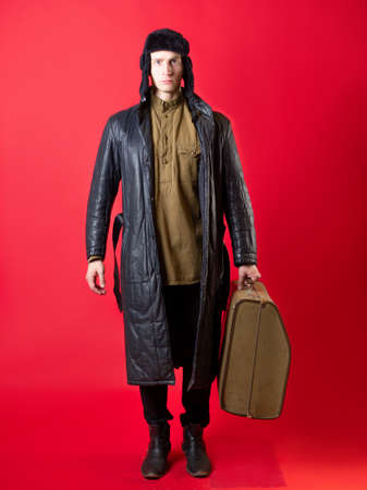 A man in old-fashioned clothes and a hat with earflaps with a large suitcase,の写真素材