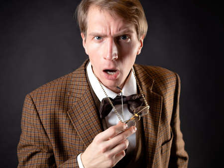 A young man in the image of a Victorian scientist, adjusts his glassesの写真素材