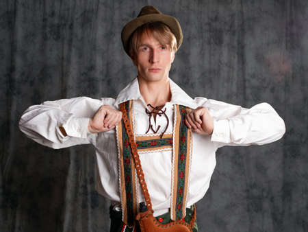 A young man in a national Bavarian suit with shorts on suspenders and a hat.の写真素材