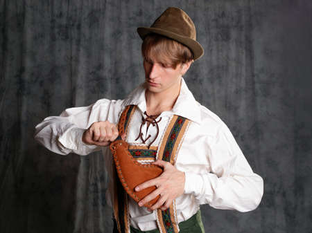 A young man in a national Bavarian suit with shorts on suspenders and a hat.の写真素材