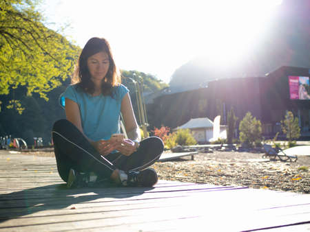 A young woman with a blue T-shirt is sitting on a treadmill,