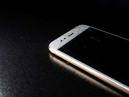 A thin white smartphone with a badly cracked screen, damage when falling.