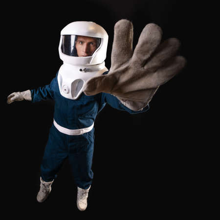 An astronaut in weightlessness reaches up with his hand.の写真素材