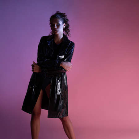 A stylish young brunette in a latex raincoat over a black bodysuit,の写真素材