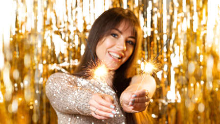 birthday or New Years eve party. Young beautiful brunette in a gold dressの写真素材