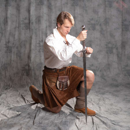 The Scottish knight knelt, took an oath, concept. A young man in a kiltの写真素材