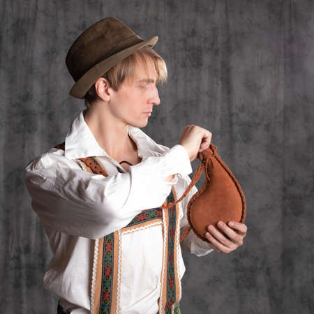 A young man in a national Bavarian suit with shorts on suspenders and a hat.