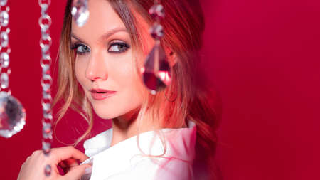 Portrait of a gorgeous young blonde among sparkling crystals, pink tone and light. Festive magical mood, celebration or New Yearの写真素材