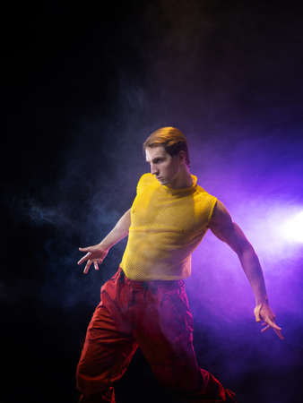 a young muscular man in a bright outfit poses in a pretentious pose, style and grotesque. Attractive...