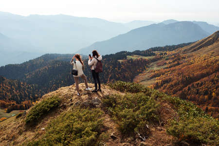 Two friends of a traveler on the top of a mountain look at a beautiful panorama, beautiful nature, the Caucasus mountains in Russiaの写真素材