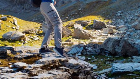 To conquer the mountains, a young man travels in the mountains, walking on rocks, legs close-up