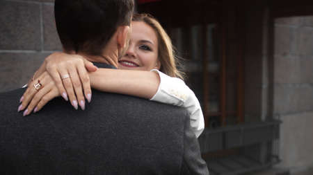 happy young blonde smiles and hugs her partner. A happy couple, a man and a woman on a city walk.