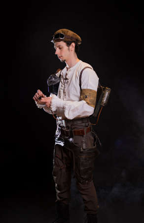 A guy in a steampunk image, a pilot or a mechanic. Retro style, fantastic image. portrait on black.