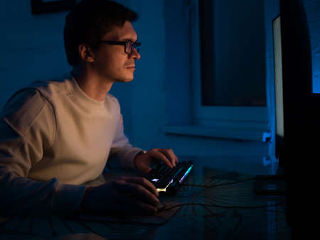 The male programmer works late. A guy with glasses is sitting in a dark office in front of a monitor...