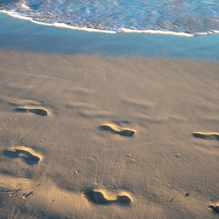 Footprints in the sand. walking by the sea. Footprints on the light sand near the surf lineの写真素材