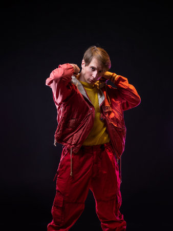 A young guy in a red youth jacket with a hood. Stylish outfit, modern style, photo on blackの写真素材