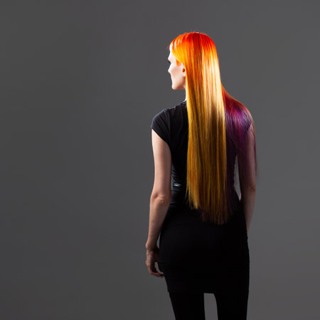 Creative hair coloring. A young woman with bright red hair with yellow and purple strandsの写真素材