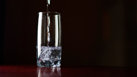 Pour a glass of water, a clear glass on the table, a stream of clean water