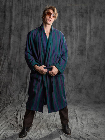 relaxed dude after a party in a housecoat with a shaggy head, posing in the studio on a gray backgroundの写真素材
