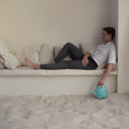 The global economic crisis, the concept of risky investments. A businessman financier with a watering can in his hands stands in the desert, a gardener fertilizes the soil where nothing growsの写真素材