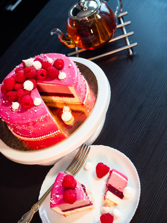 Beautiful pink cake with raspberries, sweet dessert. Home pastry chef. A piece of cake is cut off...