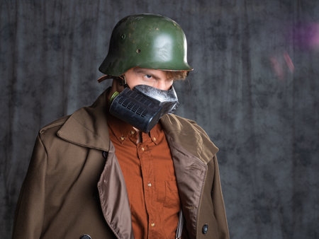 A young guy in military-style clothes, a brown outfit and a helmet on his head. Posing in the studio...