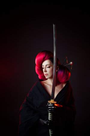 fighting geisha in a black kimono with a katana. young multiethnic woman in a bright Asian costume. voluminous hairstyle with scarlet hair and decorative hairpinsの写真素材