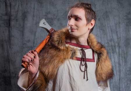 A young guy in a suit in the style of Vikings or ancient Slavs, portrait in the studio on grayの写真素材