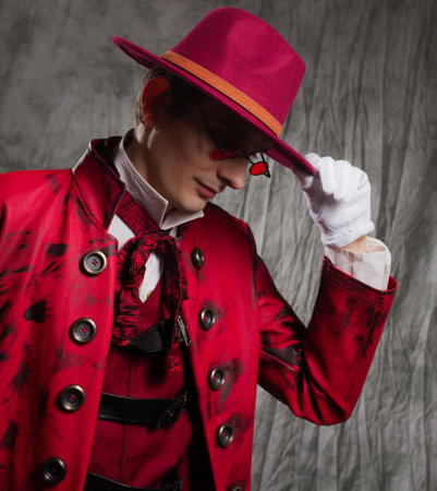A stylish guy in a vampire costume, a red hat, a coat and tinted glasses.の写真素材