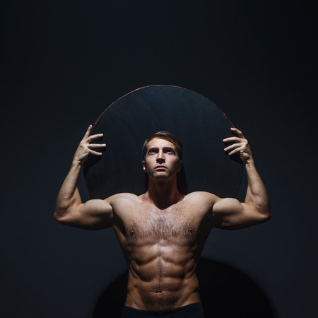 An athlete like an Atlantean, holds weight on his shoulders, a muscular athlete, the body of an ancient heroの写真素材