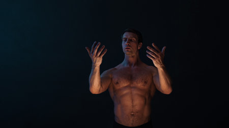 A muscular athlete in an epic pose, fog and smoke on the background, warm mystical light from below, the concept of the antique beauty of the human bodyの写真素材