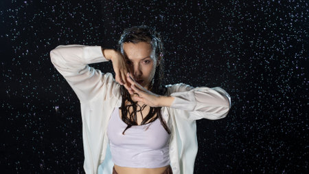 young woman in the rain, getting wet through, wet clothes and water running down her face.の写真素材