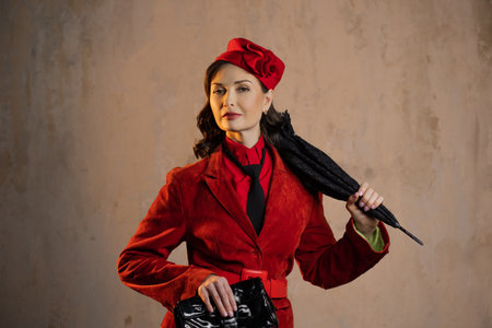 A stylish lady in a red old-fashioned suit with a hat and a lace umbrellaの写真素材