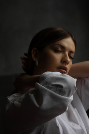 Comfortable portrait of a beautiful young woman in a white shirt, face out of focusの写真素材