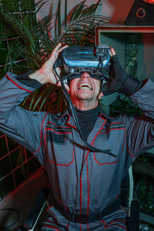 A man in overalls with a cyber helmet on his head, screams in horror while in meta reality, high technology and low standard of living of society, conceptの写真素材