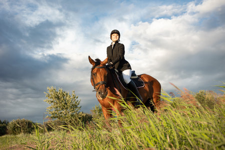 Horsewoman in equestrian sports gear, riding a horse, against an expressive sky, horseback riding in...