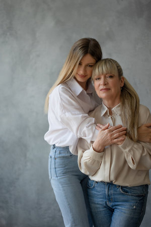 Happy family, women together. Mom and adult daughter smile at each other, studio photo in casual styleの写真素材