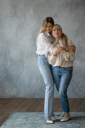 Mom and adult daughter, family portrait, two generations of women. Portrait in the studio in bright colorsの写真素材