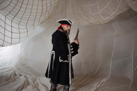 Pirate captain in an embroidered doublet and cocked hat with an antique pistol in his hand, portrait...