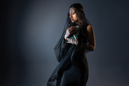 face under a black veil, a young woman in black with a book in her hands