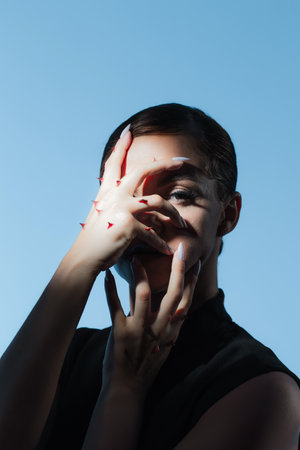 Self-criticism and self-strictness, a concept. A fashion portrait in a melancholic style, a woman with rose thorns on her arm, restrains herselfの写真素材